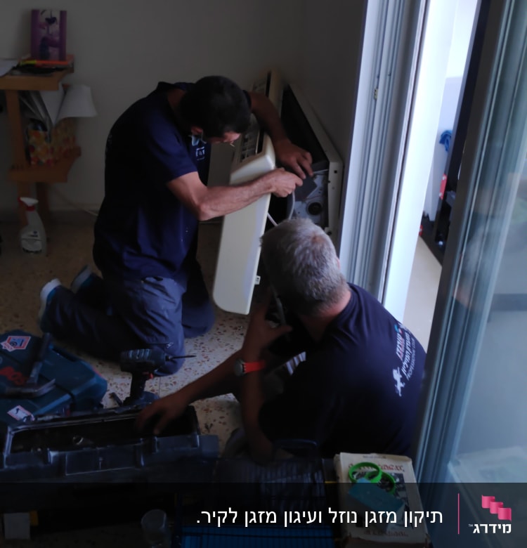 שני אנשים מתקנים מזגן עם כלים על הרצפה